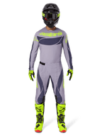 Pilote de motocross portant l'ensemble d'équipement Alpinestars 2025 Techstar Dreem en gris et gris foncé avec des accents jaune néon vifs, comprenant le maillot et le pantalon assortis, des bottes jaune néon et un casque noir, conçu pour la course tout-terrain professionnelle.