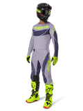 Alpinestars 2025 Techstar Dreem Gear Set, pilote de motocross en tenue de course complète, maillot et pantalon gris avec motifs gris foncé et accents jaune-vert fluo, casque noir assorti, gants et bottes jaune-vert fluo, équipement tout-terrain de performance