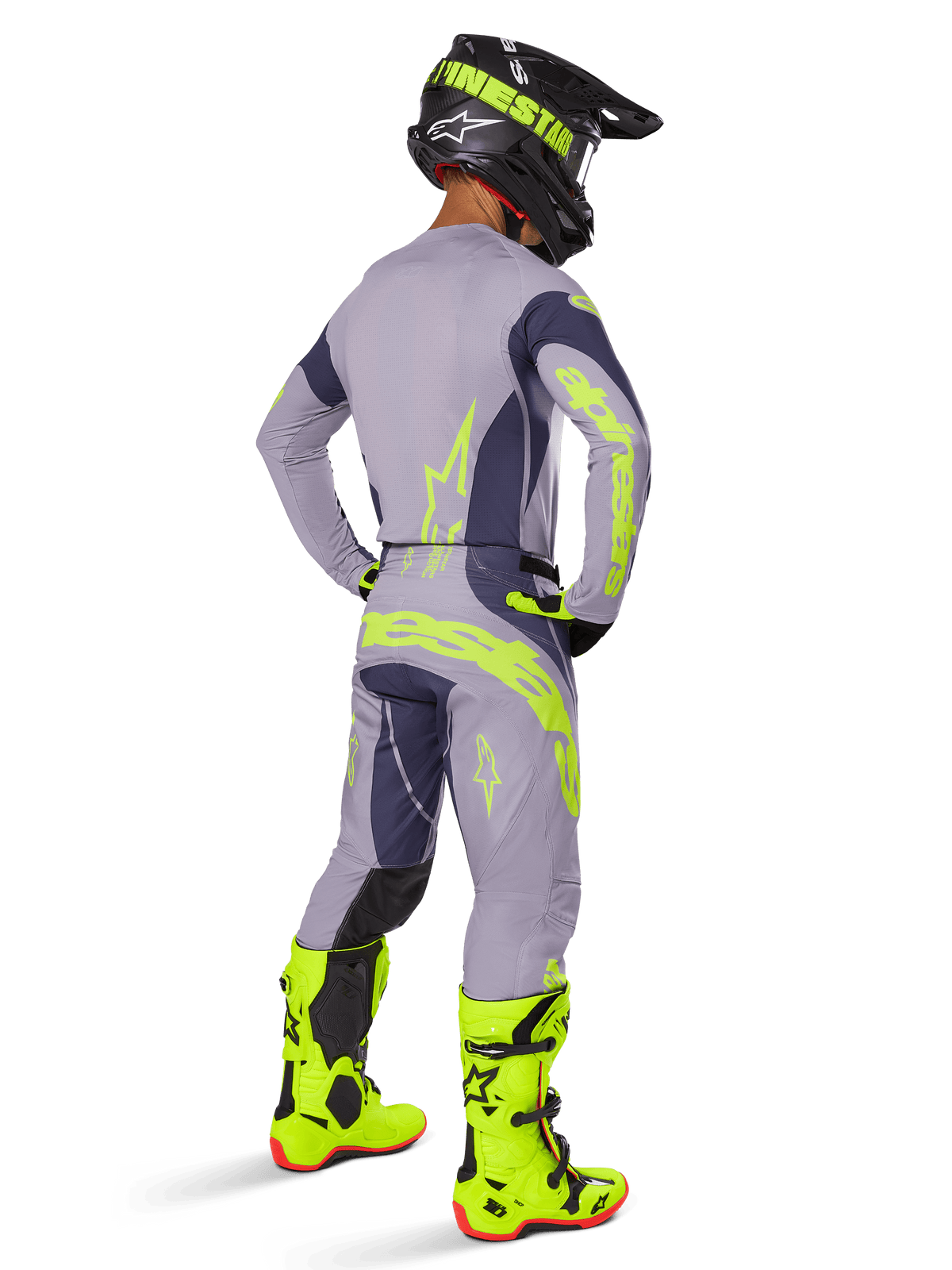 Pilote de motocross vu de dos portant l'ensemble d'équipement Alpinestars Techstar Dreem 2025, gris et gris foncé avec logos jaune fluorescent, maillot et pantalon assortis, casque noir avec accents jaunes et bottes jaune fluorescent vif, tenue de course coordonnée.