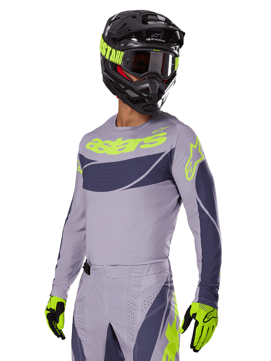 Pilote de motocross portant le maillot Alpinestars Techstar Dreem 2025, gris et gris foncé avec logos vert citron, pantalon assorti, casque noir avec accents vert citron, gants vert citron et noirs, tenue coordonnée pour la course tout-terrain