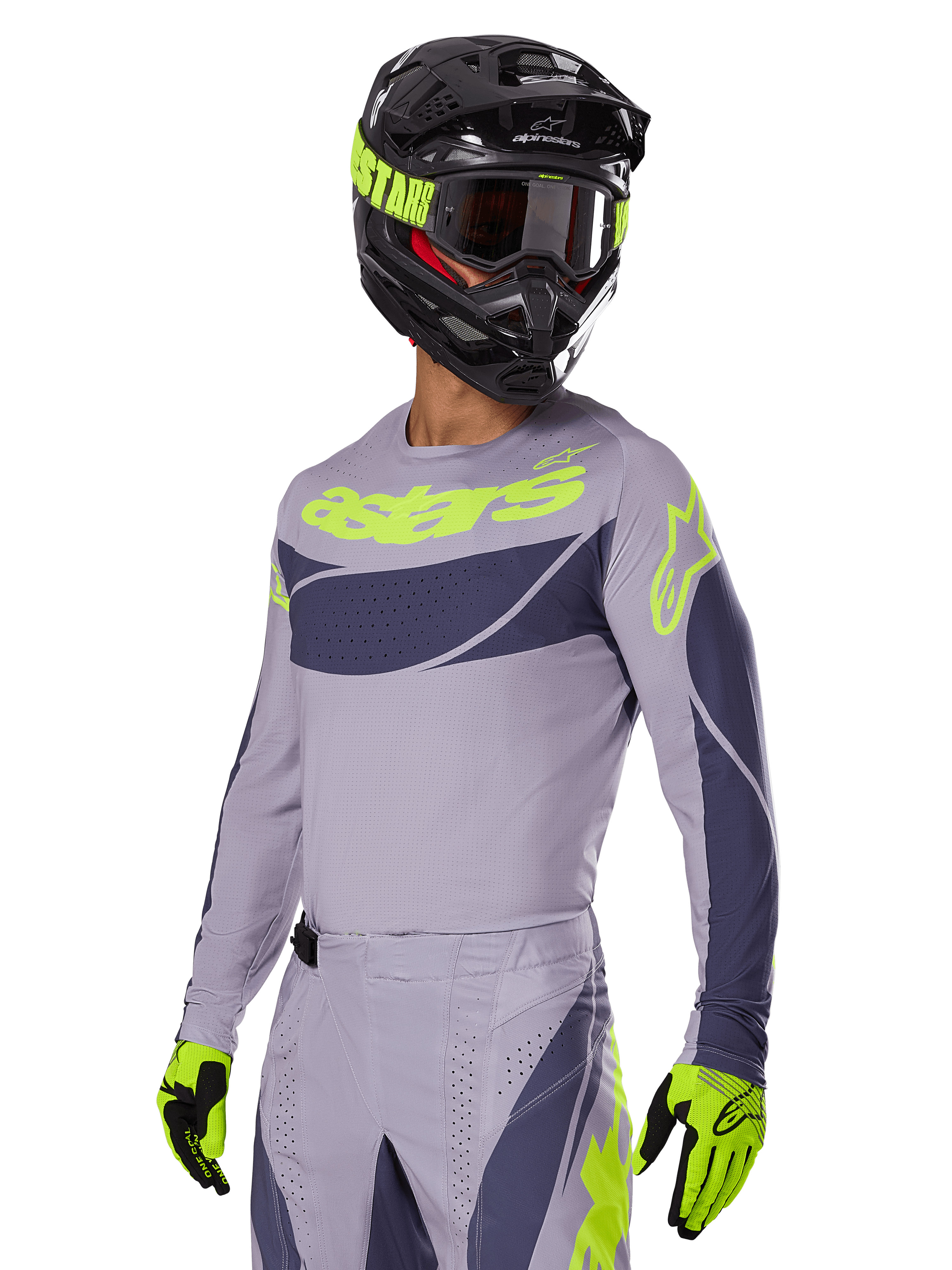 Pilote de motocross portant le maillot Alpinestars Techstar Dreem 2025 en gris et gris foncé, avec un logo 'astars' jaune fluo sur la poitrine, associé à un casque, des lunettes et des gants assortis pour un look de course tout-terrain coordonné