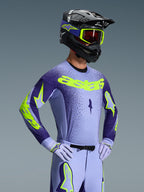 Alpinestars Supertech Scenz Gear Set 2026, pilote de motocross portant une tenue de course lavande et violet foncé avec des accents jaune néon, casque et lunettes assortis, maillot et pantalon coupe athlétique pro-fit avec logos audacieux
