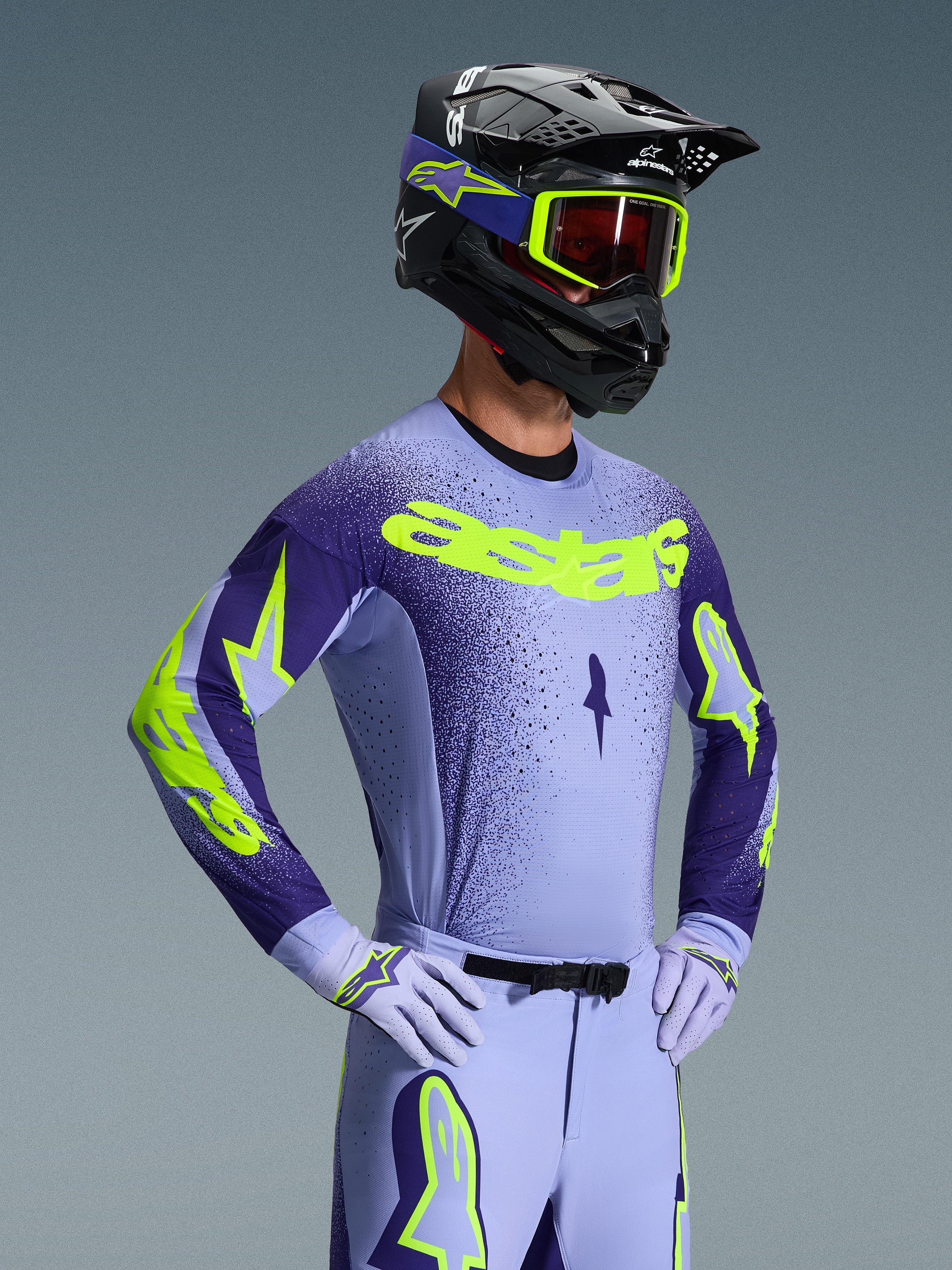 Alpinestars Supertech Scenz Gear Set 2026, pilote de motocross portant une tenue de course lavande et violet foncé avec des accents jaune néon, casque et lunettes assortis, maillot et pantalon coupe athlétique pro-fit avec logos audacieux