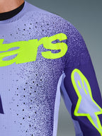 Maillot Alpinestars 2026 Supertech Scenz en violet et jaune fluo, gros plan sur la poitrine et l'épaule montrant les perforations découpées au laser, le matériau en maille extensible et le marquage jaune fluo éclatant pour une performance motocross de niveau professionnel.