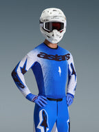 Alpinestars 2026 Supertech Scenz Jersey, Motocross Jersey, Ucla Blue and White, worn as a complete gear set with matching blue pants and gloves, featuring black 'astars' branding, white helmet and dark goggles, professional athletic racing fit.