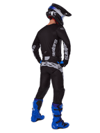 Pilote de motocross vu de dos portant l'ensemble d'équipement Alpinestars 2025 Racer Graphite, maillot et pantalon noir et gris avec logos gris, assortis à des bottes de motocross bleu vif, un casque noir et bleu et des gants bleus, tenue tout-terrain de performance complète.