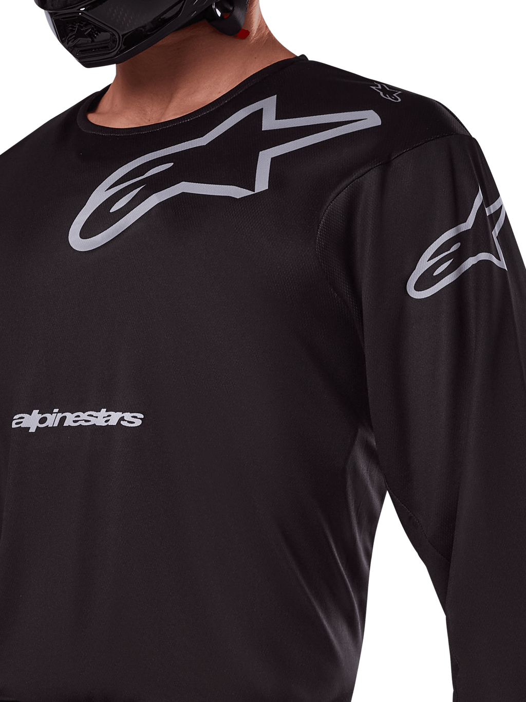 Maillot Alpinestars 2025 Racer Graphite, noir et gris, gros plan d'un pilote portant un maillot de motocross, avec marquage Alpinestars gris et logos A-star, matériau technique en poly-tissu pour la conduite tout-terrain