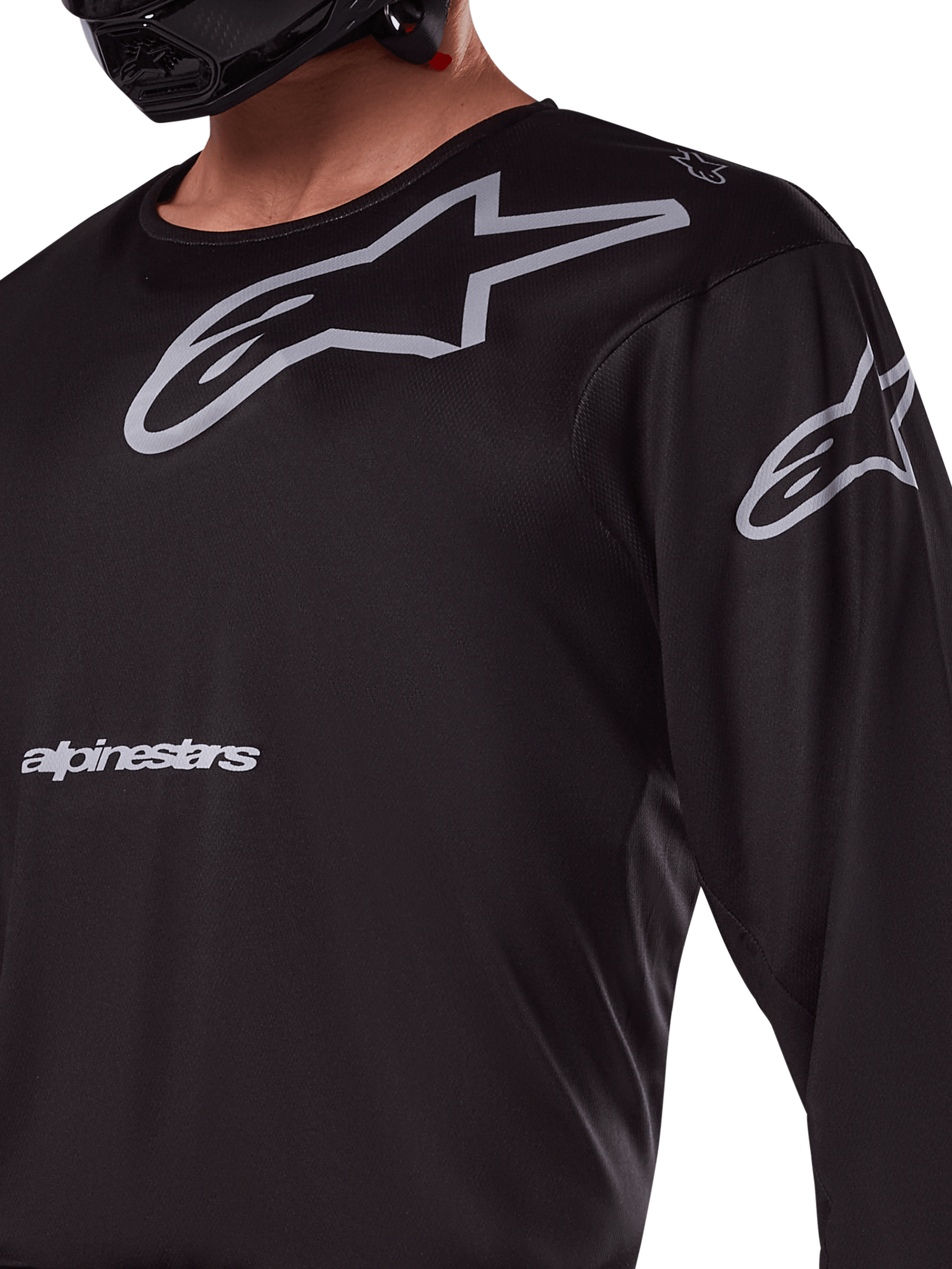 Maillot Alpinestars 2025 Racer Graphite, noir et gris, gros plan d'un pilote portant un maillot de motocross, avec marquage Alpinestars gris et logos A-star, matériau technique en poly-tissu pour la conduite tout-terrain