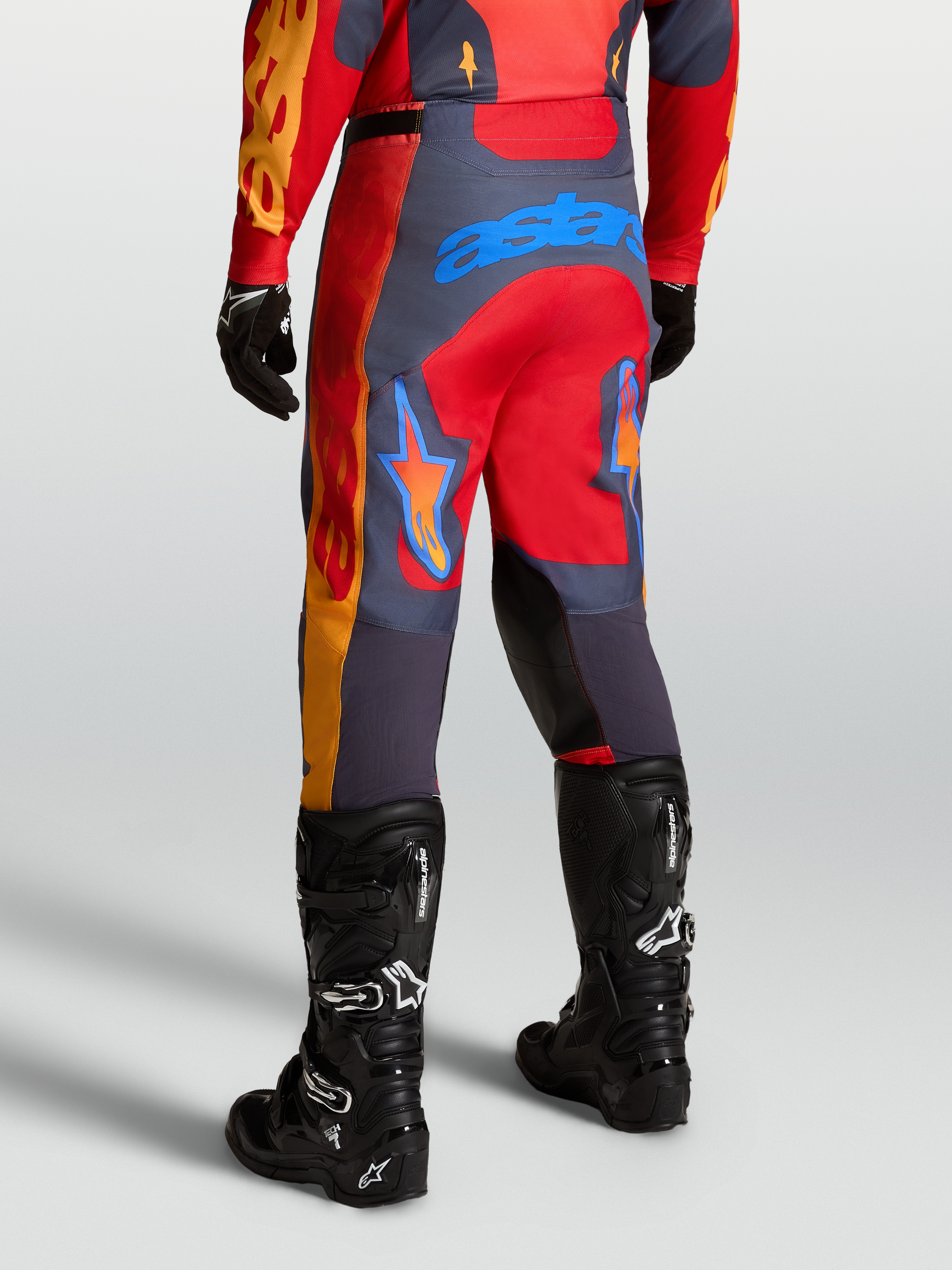 Alpinestars Pantalon Racer Hunt, pantalon de motocross performance, rouge et gris, vue arrière sur mannequin en bottes, inserts en tissu ripstop extensible et genoux renforcés pour la course off-road