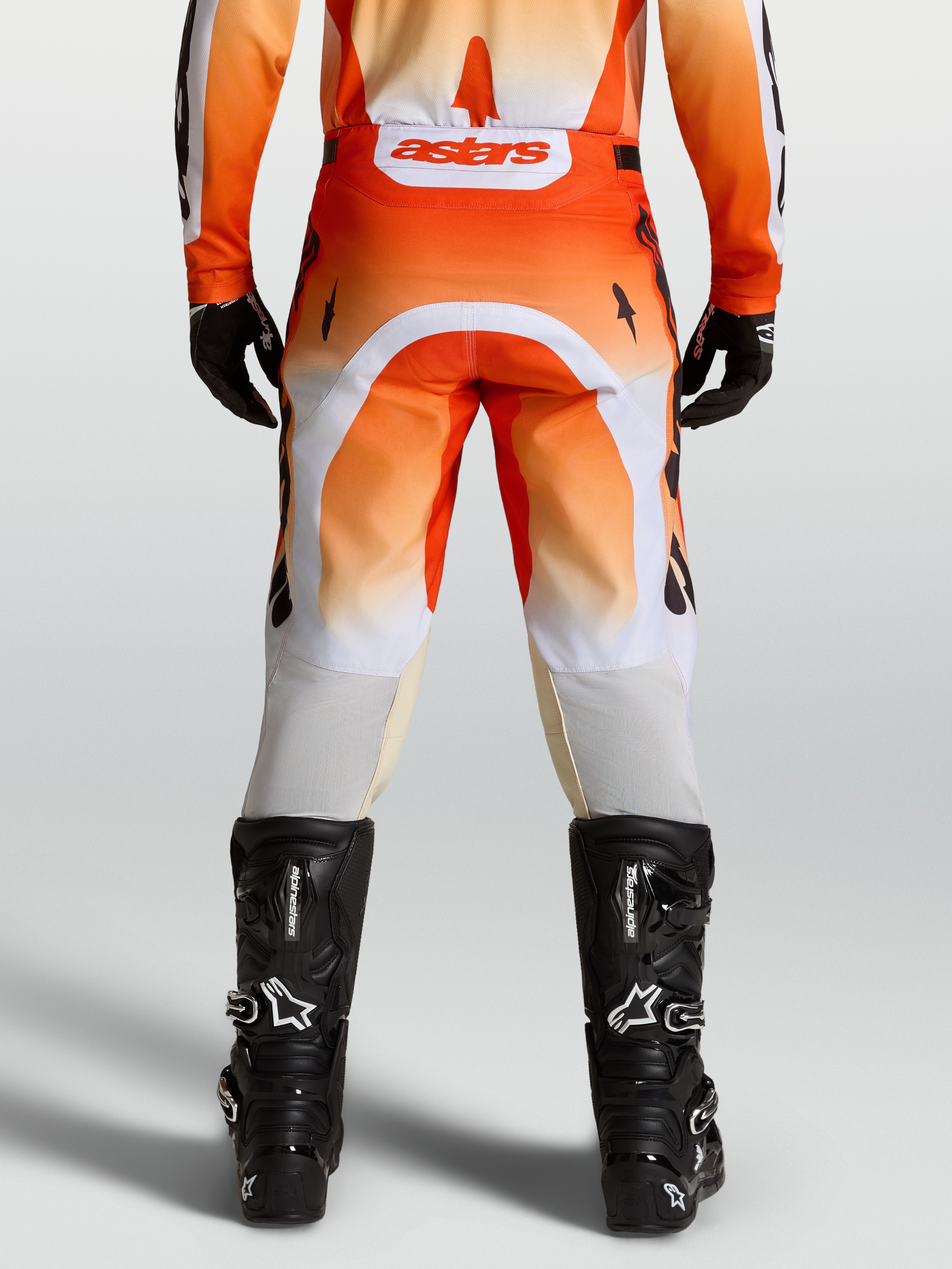 Alpinestars Racer Amber Pants, red and white motocross pants shown from the rear on-model with black boots.