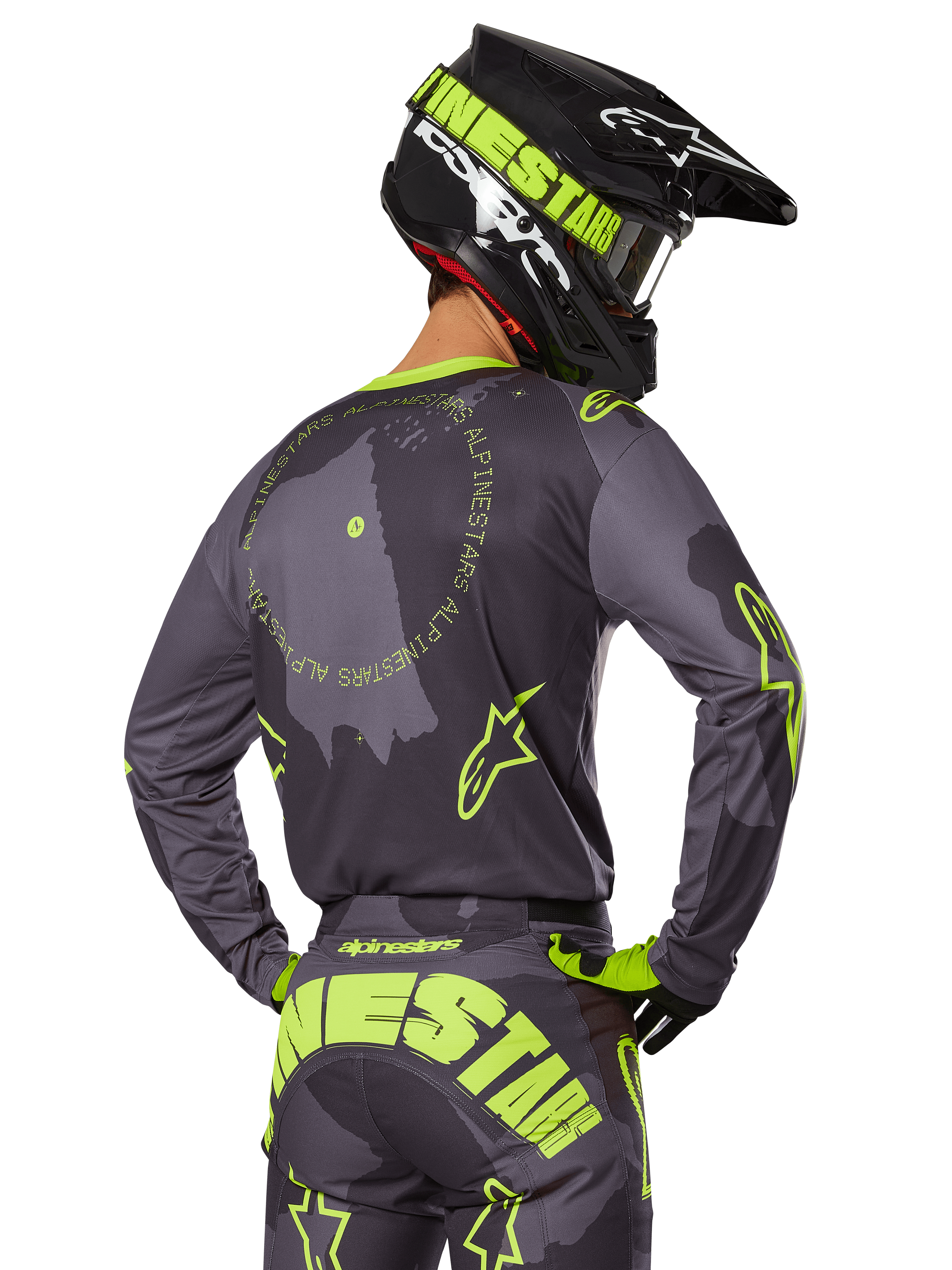 Motocross rider seen from behind wearing the 2025 Racer Hollow Gear Set, Gray jersey with fluorescent yellow circular text and star logos, matching gray and yellow pants with bold branding across the seat, black and lime green helmet, coordinated outfit for off-road racing