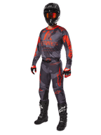 Tenue de motocross complète Alpinestars, maillot et pantalon Racer Hollow 2025 en Gris Camo Orange Fluo, casque noir avec lunettes orange, gants noirs et rouges, bottes noires avec logos blancs, équipement de course coordonné pour le tout-terrain
