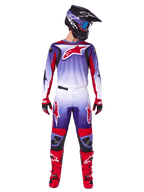 Pilote de motocross portant un équipement de course Alpinestars complet, Maillot Fluid Wurx 2025 violet et rouge vif avec accents blancs et grand logo d'étoile rouge, pantalon assorti, bottes rouges et casque noir avec lunettes, tenue coordonnée pour la course tout-terrain