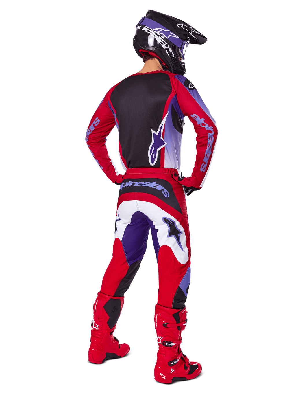 Pilote de motocross de dos portant l'ensemble Alpinestars 2025 Fluid Wurx, maillot Purple Bright Red avec panneau arrière noir, pantalon de motocross assorti avec accents blancs et violets, bottes rouge vif et casque noir, tenue de course tout-terrain professionnelle