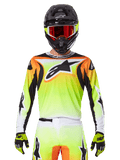 Maillot Alpinestars 2025 Fluid Wurx, maillot de motocross, jaune néon, orange et blanc, porté avec un pantalon assorti et un casque noir avec des lunettes rouges, ensemble complet d'équipement MX sur le pilote