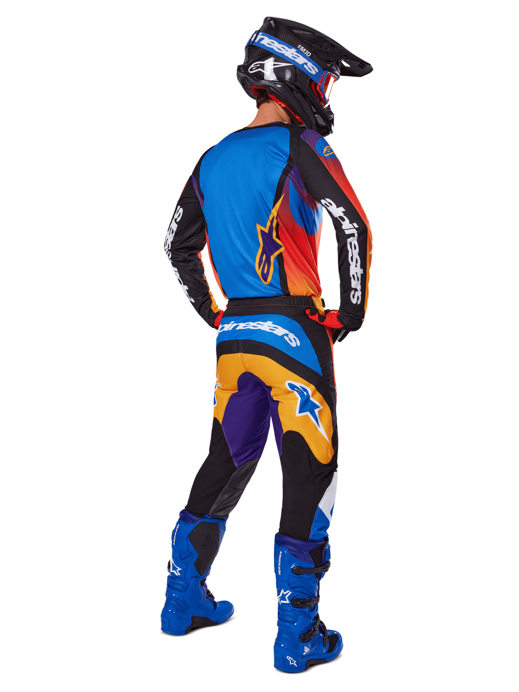 Motocross rider viewed from the back wearing Alpinestars 2025 Fluid Wurx Gear Set, multicolor jersey with blue orange and purple panels, matching pants with white Alpinestars logo on the seat, bright blue boots and a black helmet, coordinated outfit for off-road racing