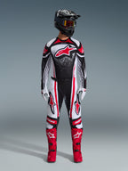 Motocross rider wearing the 2026 Techstar Nomur Gear Set, Black White and Red, jersey featuring a large red star logo and speckled pattern, matching pants with red side panels, black helmet with tinted goggles, and red motocross boots.