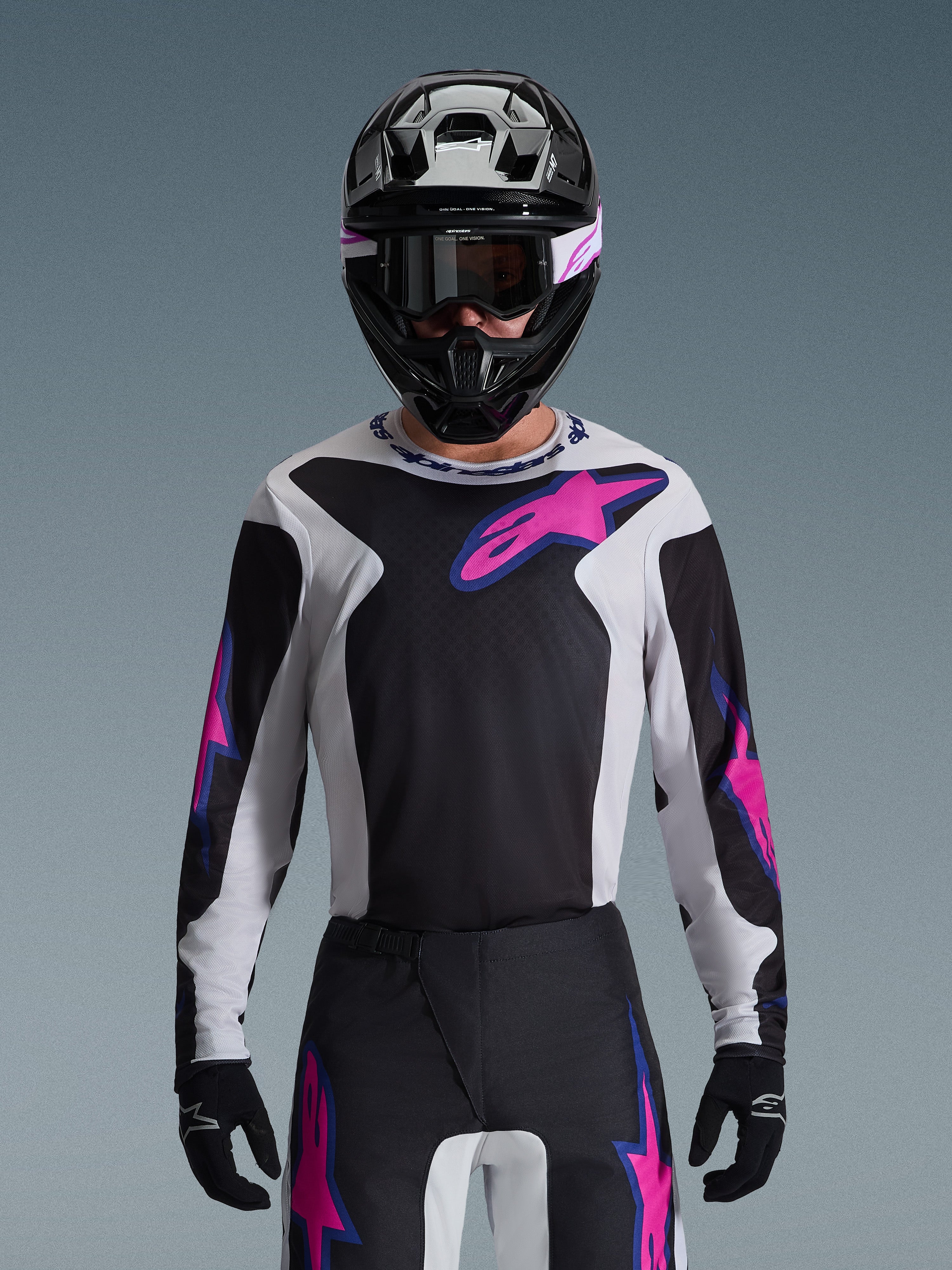 Alpinestars 2026 Fluid Grid Jersey, Motocross Jersey, Black Light Gray and Purple, worn by a rider with matching off-road pants, black helmet, and goggles, complete performance racing gear set