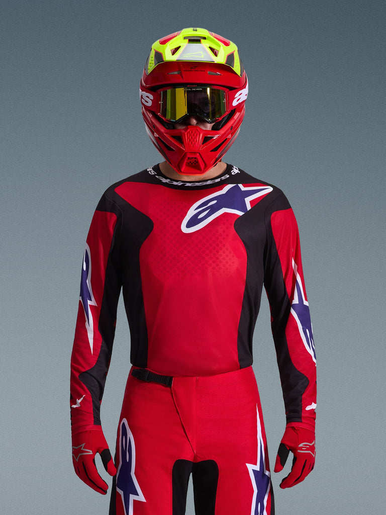 Alpinestars 2026 Fluid Grid Jersey, Motocross Jersey, Red Black and Purple, worn by a rider with a red and neon yellow helmet and gold goggles, featuring large star logos on the chest and sleeves, coordinated gear for off-road racing