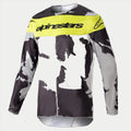 Alpinestars 2023 Racer Tactical Jersey, maillot de motocross, camouflage gris et jaune fluo, présentant un motif camouflage gris et noir avec un panneau jaune vif sur la poitrine et le logo Alpinestars, équipement de performance à manches longues robuste pour les courses tout-terrain