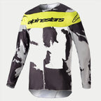Alpinestars 2023 Racer Tactical Jersey, maillot de motocross, camouflage gris et jaune fluo, présentant un motif camouflage gris et noir avec un panneau jaune vif sur la poitrine et le logo Alpinestars, équipement de performance à manches longues robuste pour les courses tout-terrain