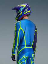 Maillot Alpinestars Fluid Apex 2026, Bleu Jaune Fluo, vue arrière d'un pilote portant un pantalon de motocross et un casque assortis, avec des motifs géométriques jaune fluo et une coupe athlétique décontractée, équipement de course tout-terrain coordonné