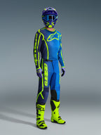 Motocross rider wearing the Alpinestars 2026 Fluid Apex Gear Set, blue and navy jersey with bright yellow accents and chest logo, matching pants with bold yellow 'astars' lettering, neon yellow and black boots, purple gloves, and a blue and purple helmet with coordinated goggles.