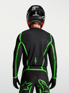 Alpinestars Fluid Apex V2 Jersey for motocross, black and fluorescent green, rear view on model showing extended back coverage.