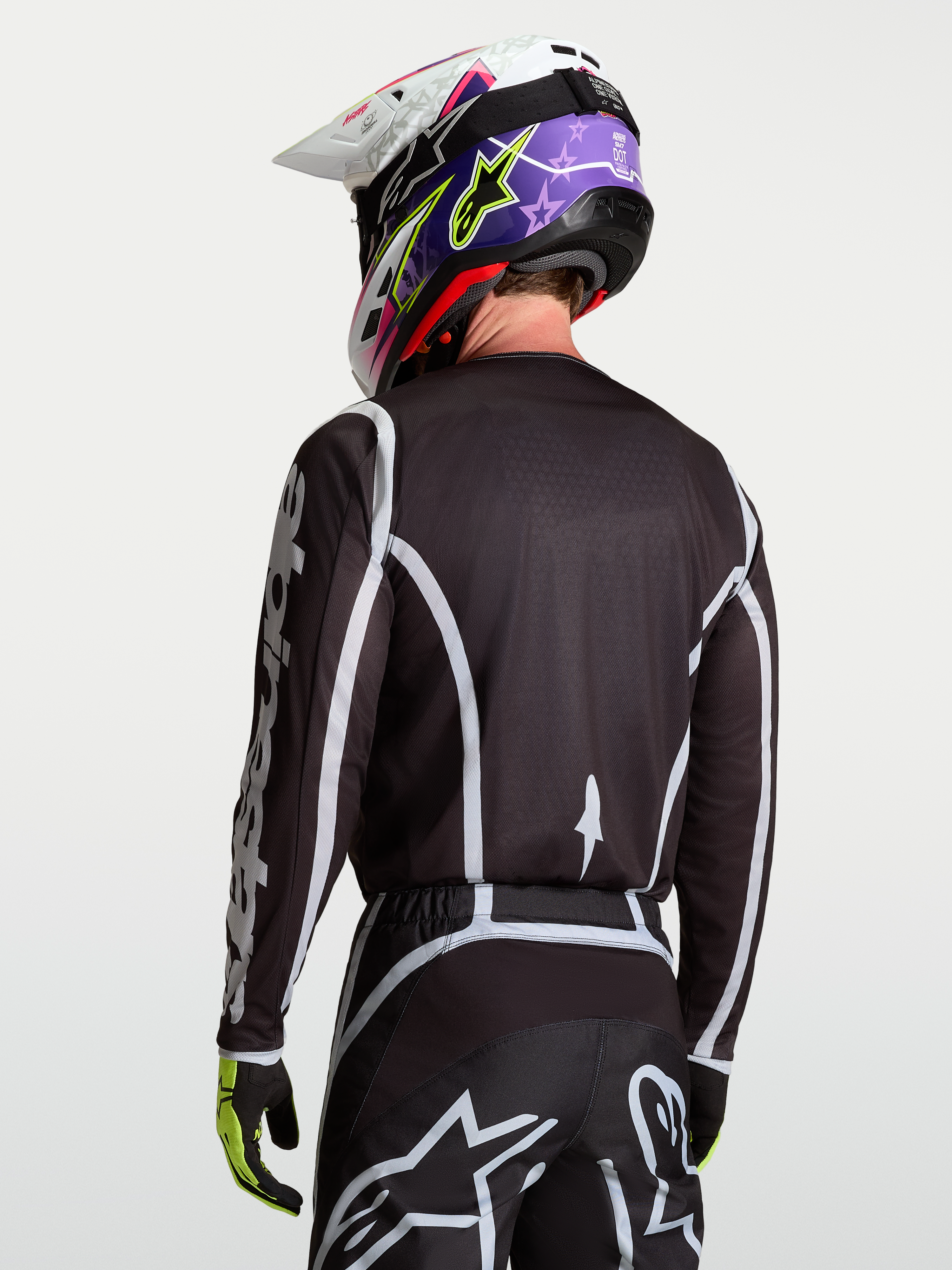 Alpinestars Fluid Apex V2 Jersey, Black and Silver motocross racing top on model viewed from the back, featuring moisture-wicking polyfabric and ergonomic cut.