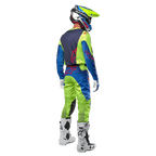 Motocross rider from behind wearing the Alpinestars 2024 Racer Hoen Jersey in Yellow Fluo and Blue Night Navy, matching motocross pants and white boots, showing the rear design with red logos, coordinated outfit for professional off-road racing
