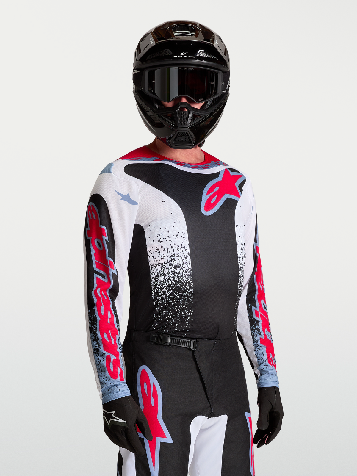 Alpinestars Maillot Fluid Drag, maillot de motocross tout-terrain pour homme, noir, blanc et rouge, en textile léger et respirant, porté par un pilote.