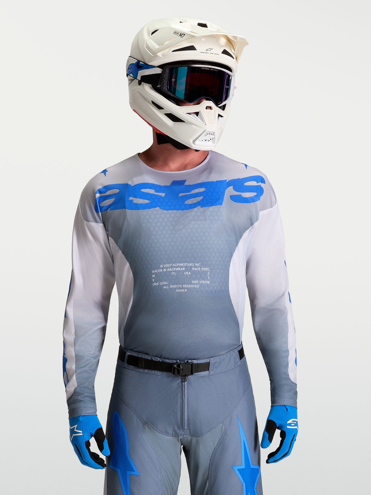 Alpinestars Maillot Racer Amber, maillot de motocross pour homme, gris et bleu, porté avec casque et masque blancs, équipement tout-terrain haute performance