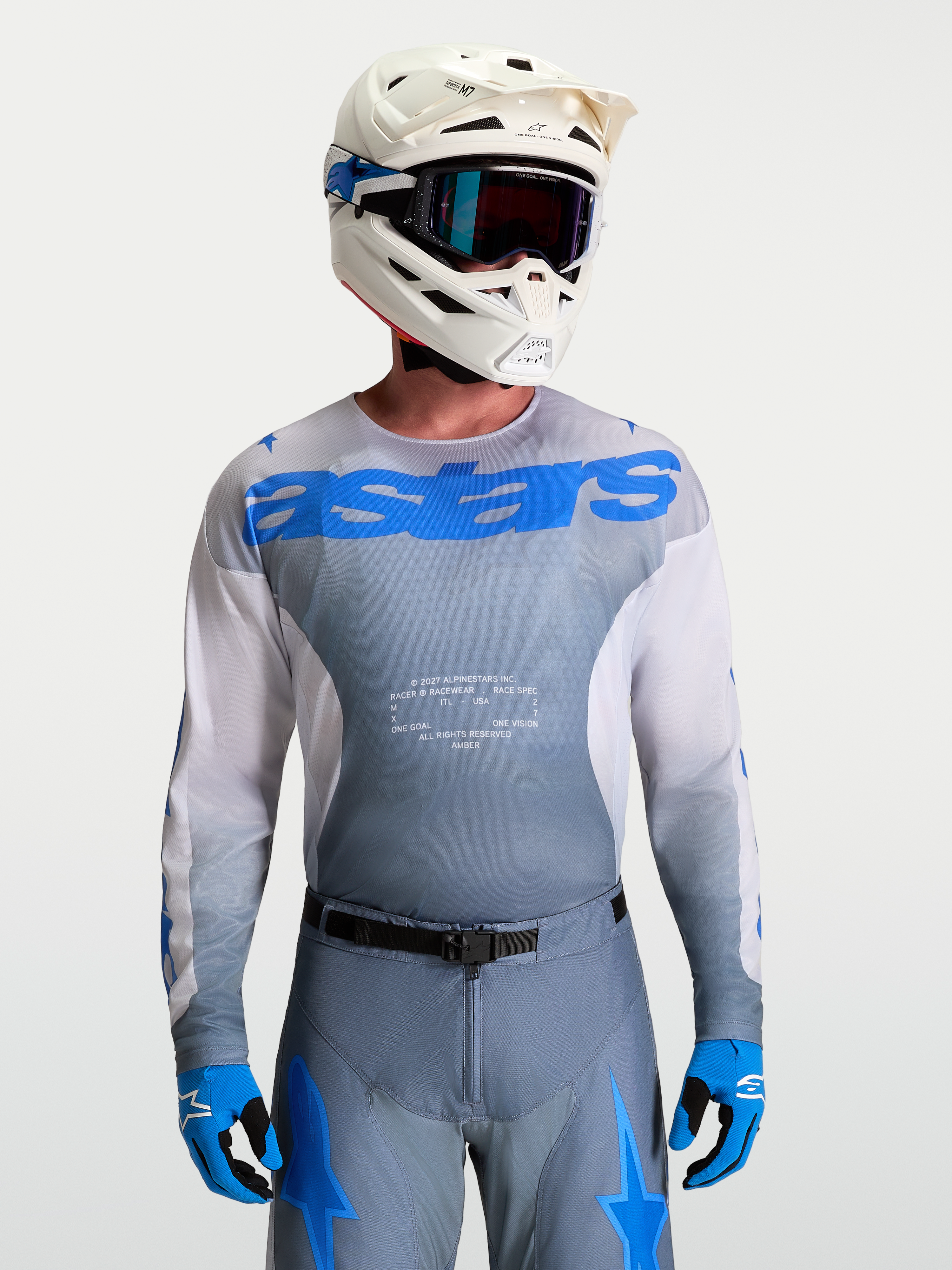 Alpinestars Maillot Racer Amber, maillot de motocross pour homme, gris et bleu, porté avec casque et masque blancs, équipement tout-terrain haute performance