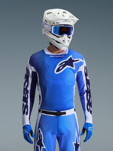 Alpinestars Racer Air Portl Jersey 2026 en bleu Ucla et blanc, maillot de motocross avec construction en maille respirante et logo étoile distinctif, porté avec un pantalon assorti, un casque blanc et des lunettes bleues, tenue de course tout-terrain coordonnée.