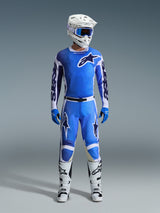 Pilote de motocross portant le maillot Alpinestars 2026 Racer Air Portl en Ucla Blue White, associé à un pantalon de motocross bleu assorti, un casque blanc avec des lunettes bleues, des gants bleus et des bottes blanches, équipement professionnel complet pour la course tout-terrain