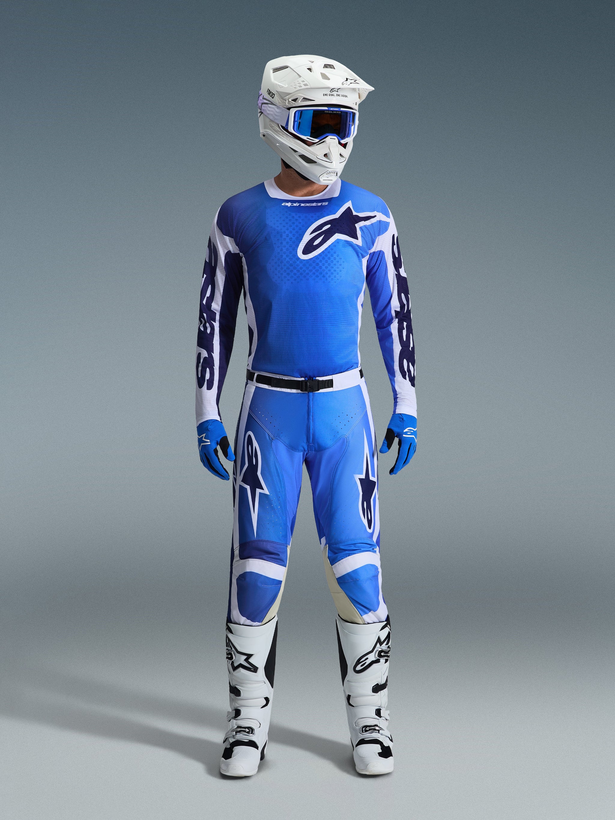 Pilote de motocross portant le maillot Alpinestars 2026 Racer Air Portl en Ucla Blue White, associé à un pantalon de motocross bleu assorti, un casque blanc avec des lunettes bleues, des gants bleus et des bottes blanches, équipement professionnel complet pour la course tout-terrain