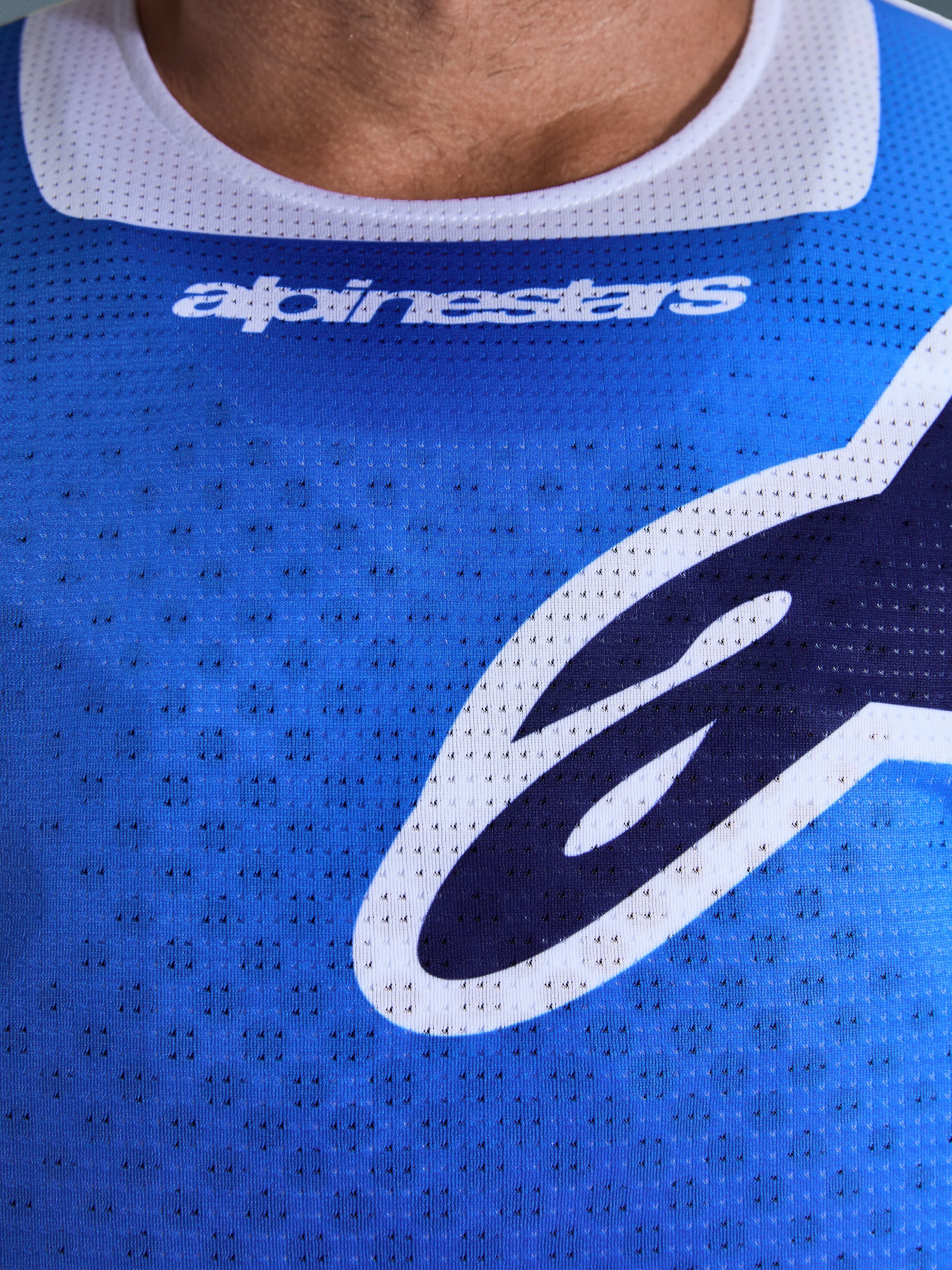 Alpinestars 2026 Racer Air Portl Jersey, maillot de motocross, bleu UCLA et blanc, gros plan sur la poitrine montrant le tissu en maille perforée respirante, bordure de col blanche et logos Alpinestars stylisés