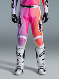 Alpinestars 2026 Racer Air Portl Pants, pantalon de motocross, dégradé vibrant de violet, rose et orange, avec des logos d'étoiles sur les cuisses, porté avec des bottes de course blanches et des gants noirs, conçu pour la conduite tout-terrain haute performance