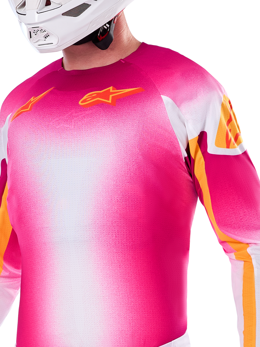 Maillot Alpinestars Édition Limitée Supertech AFD MIG, maillot de motocross avec dégradé rose fluo et blanc, logos Astars orange et accents sur les manches, porté par un pilote avec un casque blanc, coupe de course athlétique