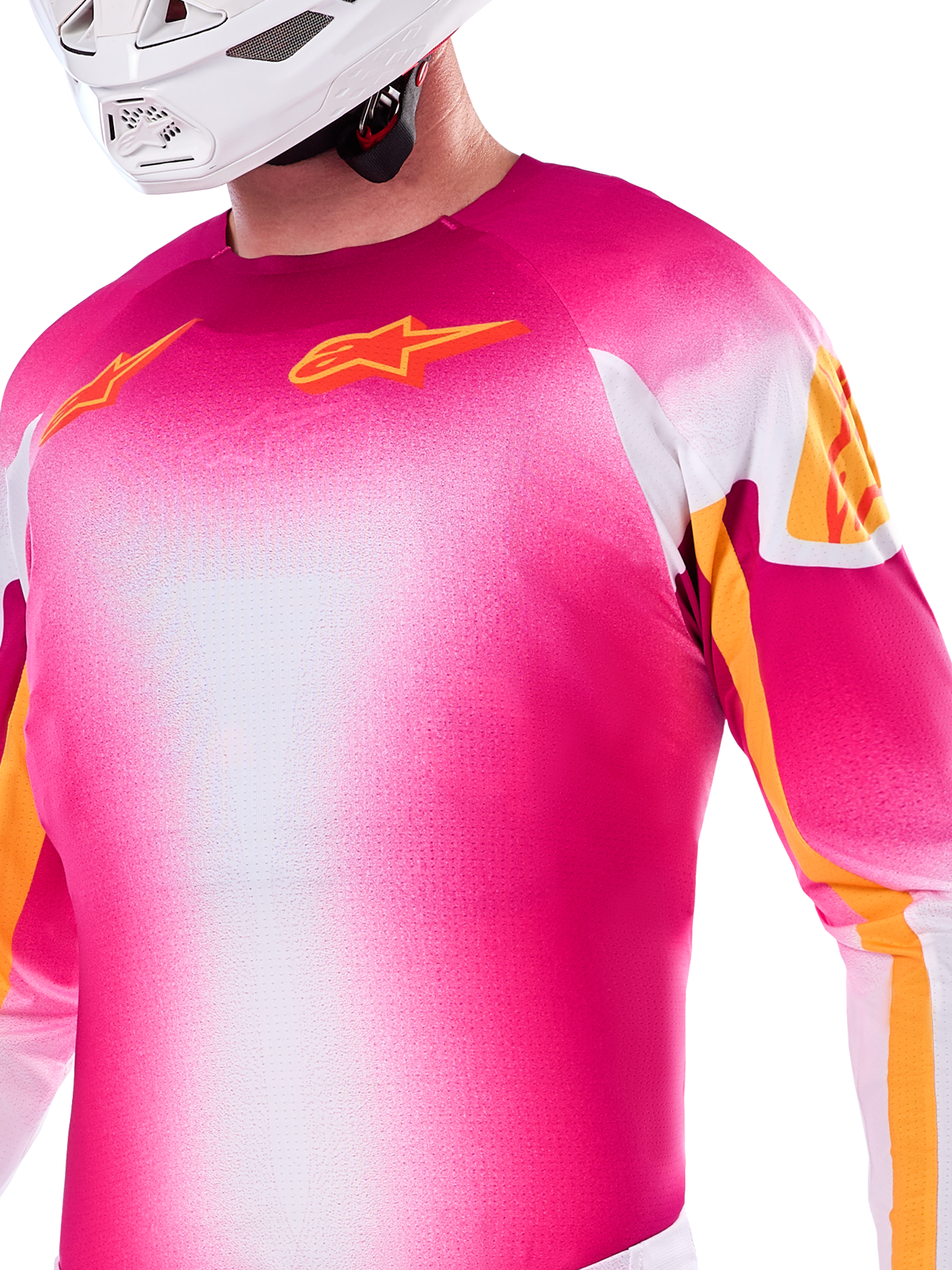 Maillot Alpinestars Édition Limitée Supertech AFD MIG, maillot de motocross avec dégradé rose fluo et blanc, logos Astars orange et accents sur les manches, porté par un pilote avec un casque blanc, coupe de course athlétique
