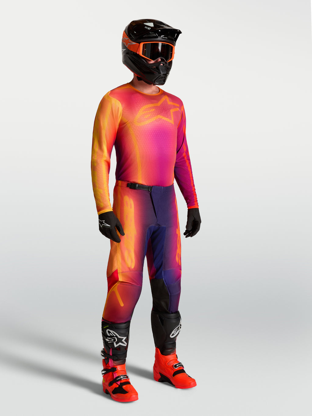Maillot Fluid Kepler Alpinestars, maillot de motocross violet et orange porté par un mannequin avec équipement de course assorti, poly-tissu technique léger.