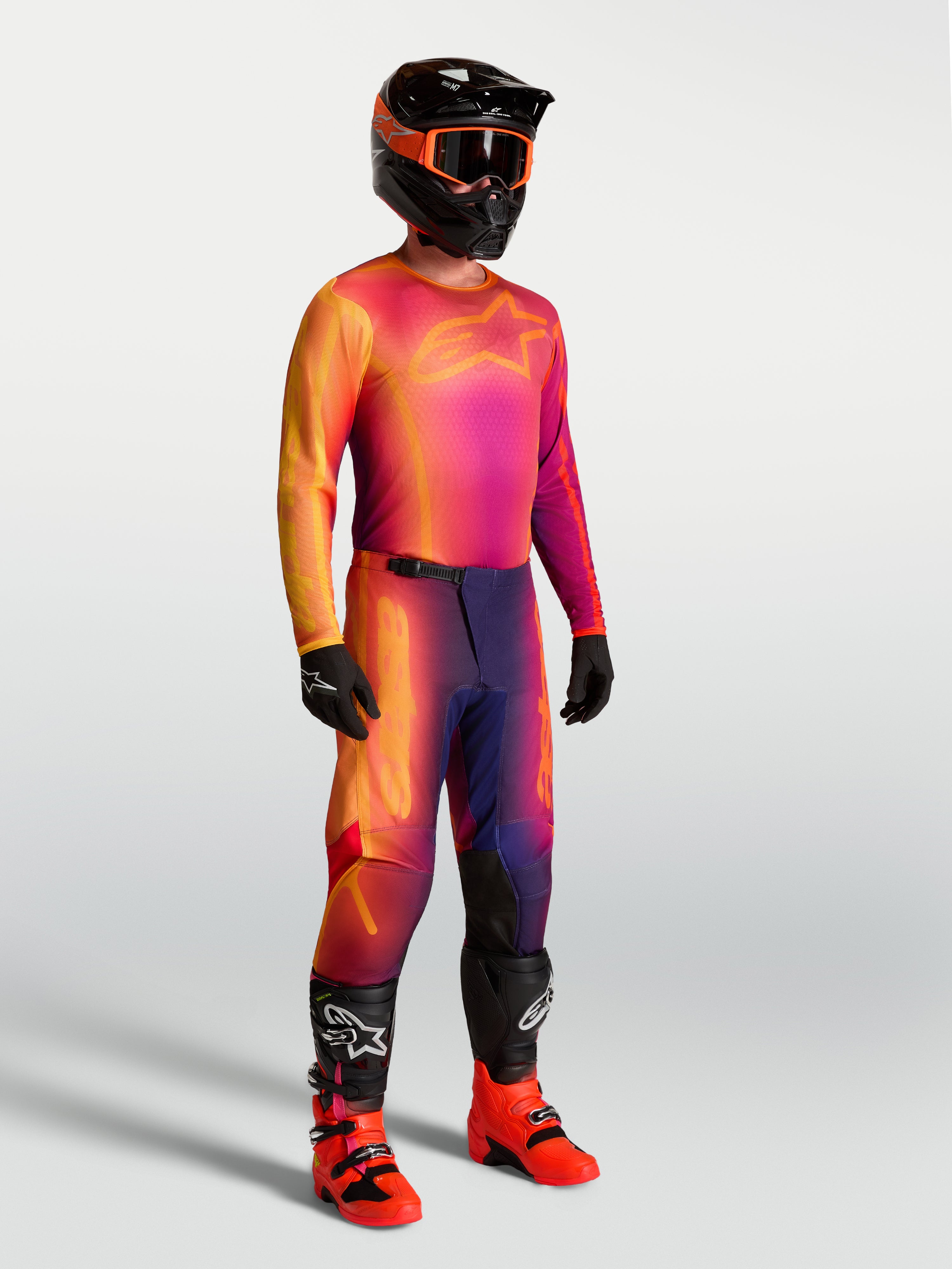 Maillot Fluid Kepler Alpinestars, maillot de motocross violet et orange porté par un mannequin avec équipement de course assorti, poly-tissu technique léger.