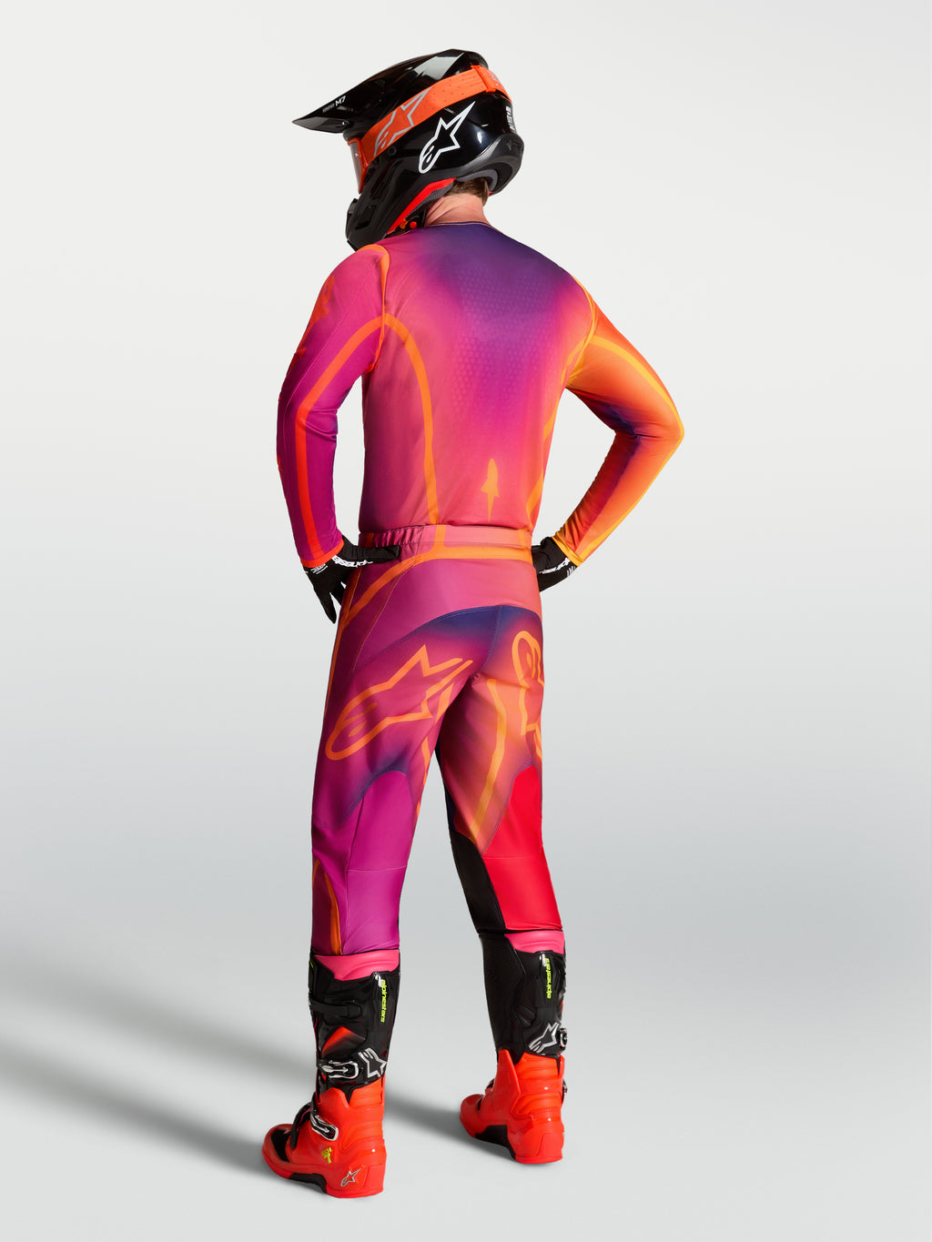 Maillot Fluid Kepler Alpinestars, maillot de motocross violet et orange, vue de dos sur un pilote en tenue complète.