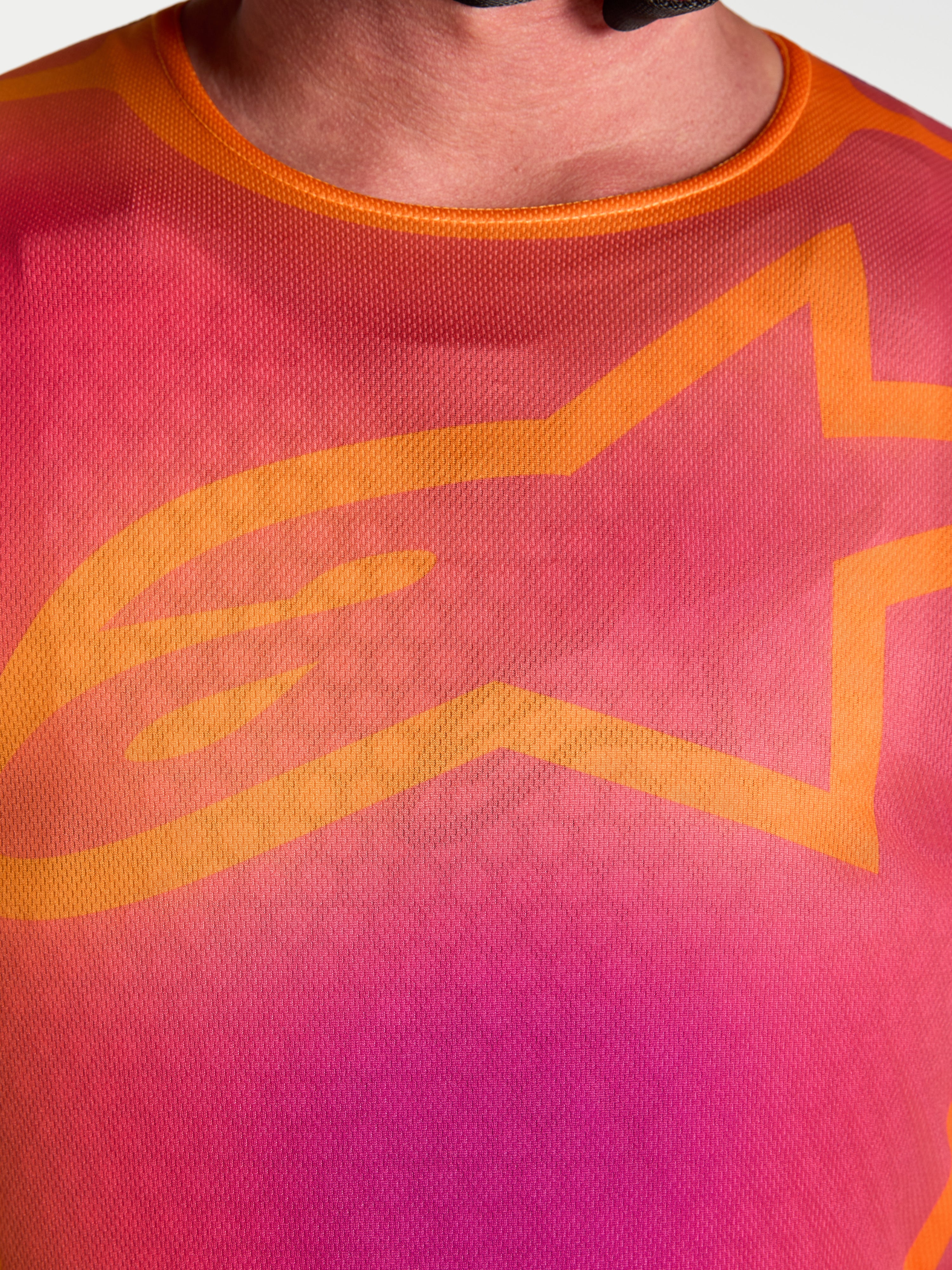 Maillot Alpinestars Fluid Kepler, maillot de motocross pour homme, violet et orange, gros plan sur le logo A-star orange.