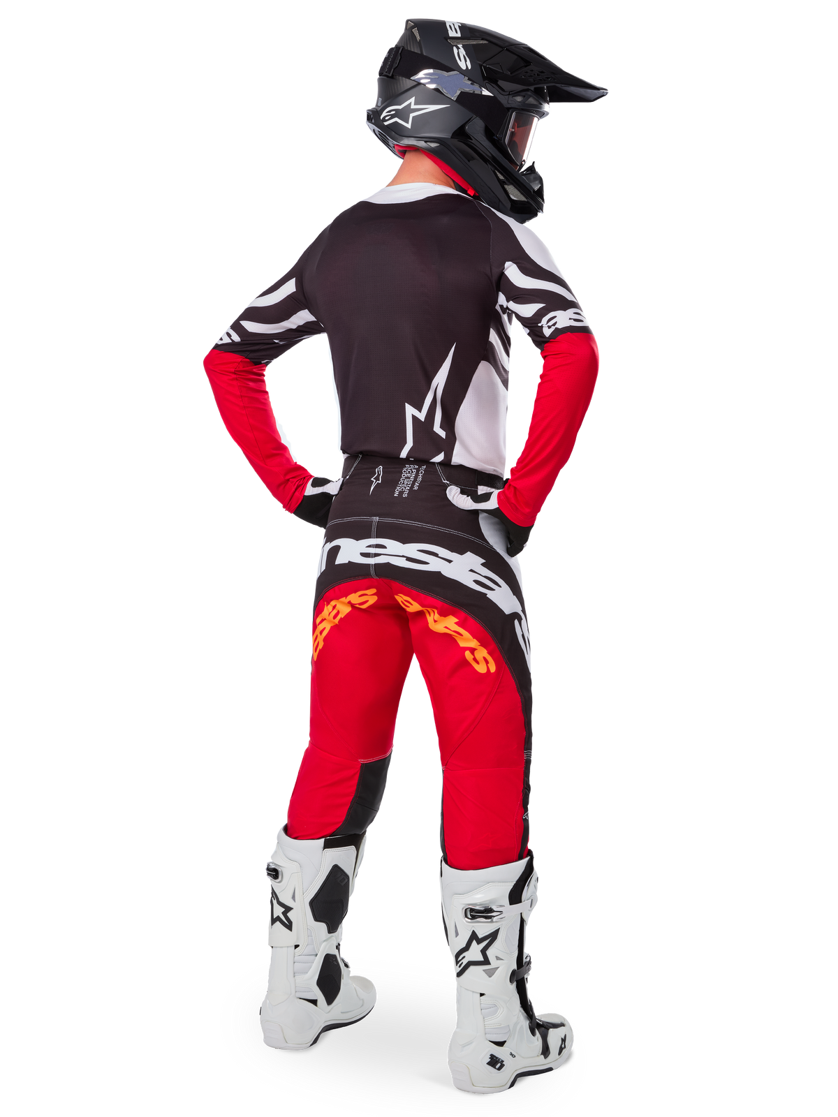 Pilote de motocross vu de dos portant le maillot Alpinestars Limited Edition Techstar Deep en Noir Blanc Rouge Intense, avec un dos noir orné d'un logo étoile blanc et des manches rouges, associé à un pantalon assorti rouge et noir, des bottes blanches et noires et un casque noir pour une tenue complète de course tout-terrain.