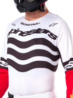 Maillot Alpinestars Techstar Deep Limited Edition, maillot de motocross blanc avec rayures horizontales noires ondulées et manches rouges, logos Alpinestars et Techstar, petites perforations découpées au laser sur la partie supérieure de la poitrine pour la ventilation, équipement tout-terrain athlétique