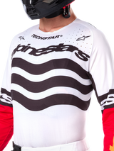 Maillot Alpinestars Techstar Deep Limited Edition, maillot de motocross blanc avec rayures horizontales noires ondulées et manches rouges, logos Alpinestars et Techstar, petites perforations découpées au laser sur la partie supérieure de la poitrine pour la ventilation, équipement tout-terrain athlétique
