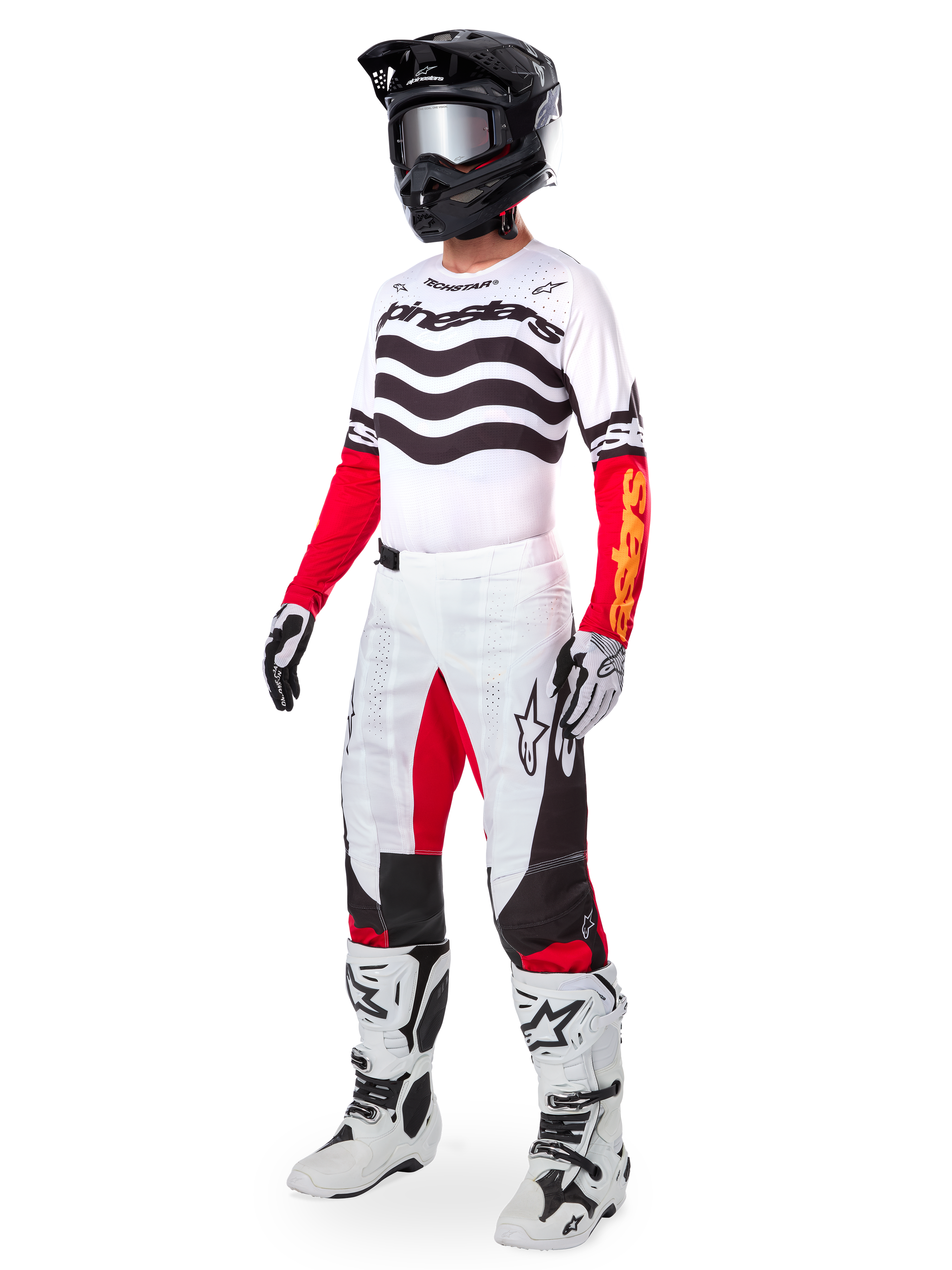 Pilote de motocross portant un équipement de course complet, Maillot Techstar Deep Limited Edition avec des rayures ondulées blanches et noires et des manches rouges, pantalon blanc et rouge assorti, casque noir, bottes blanches et noires, tenue coordonnée pour la course tout-terrain