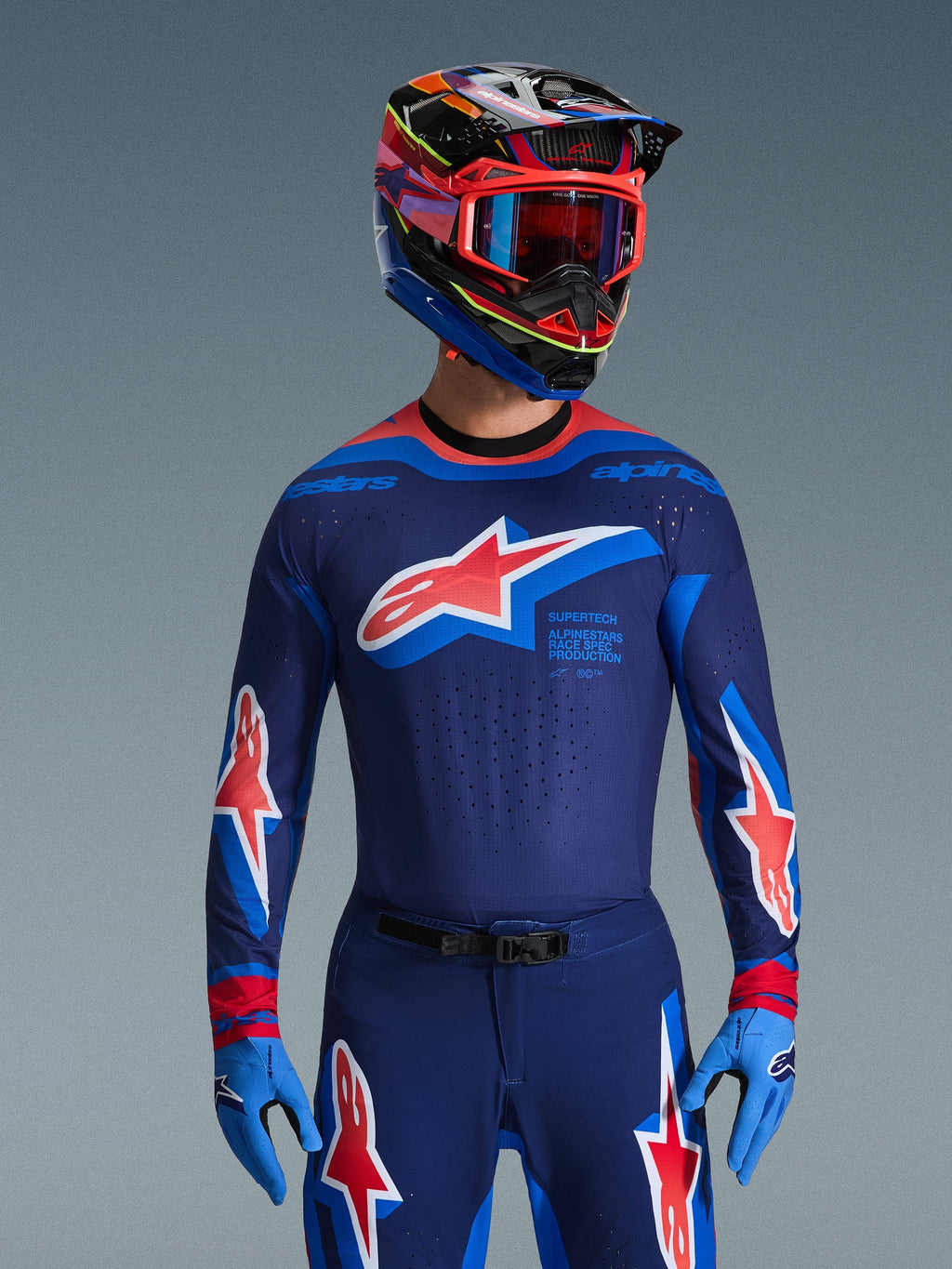 Maillot Alpinestars Supertech Vista 2026, maillot de motocross, bleu marine foncé, Hot Coral et Cobalt, porté avec un pantalon et un casque de motocross assortis, avec un grand logo étoile sur la poitrine et le marquage race spec, coupe athlétique avec panneaux en mesh ventilés pour une performance de course d'élite