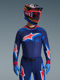 Maillot Alpinestars Supertech Vista 2026, maillot de motocross, bleu marine foncé, Hot Coral et Cobalt, porté avec un pantalon et un casque de motocross assortis, avec un grand logo étoile sur la poitrine et le marquage race spec, coupe athlétique avec panneaux en mesh ventilés pour une performance de course d'élite